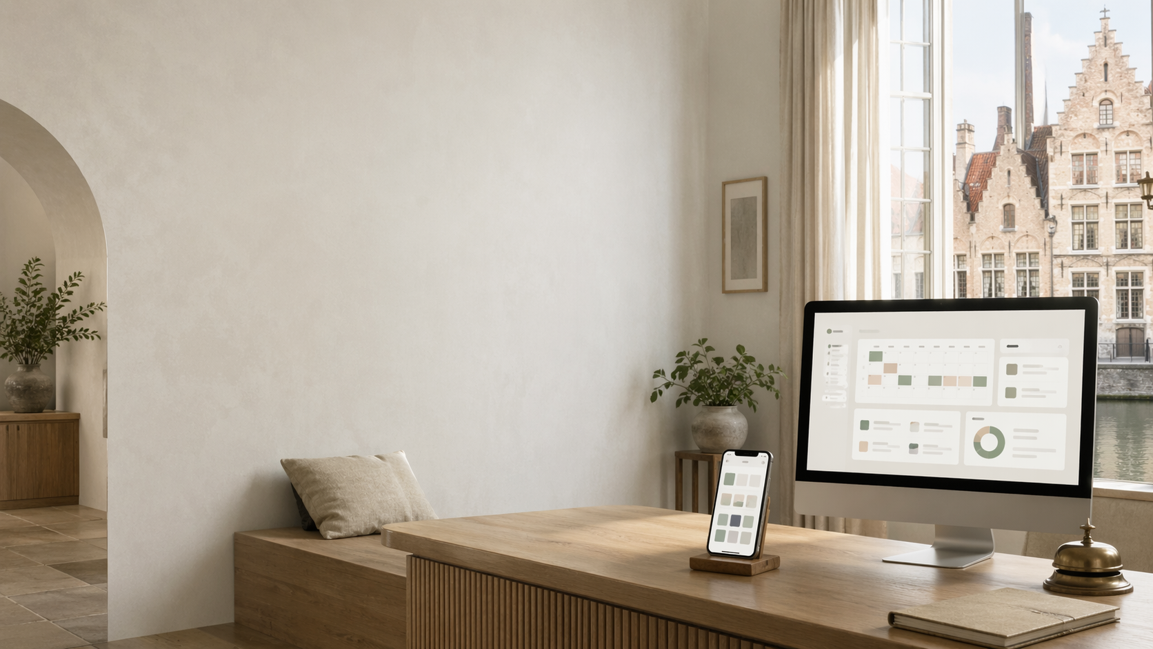 Revenue dashboard on a workspace monitor with companion phone showing rate tiles, soft natural light